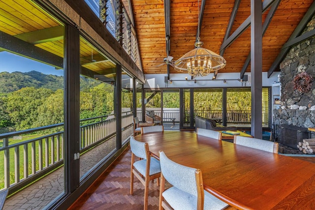 unfurnished sunroom with wood ceiling, a stone fireplace, lofted ceiling with beams, and a notable chandelier