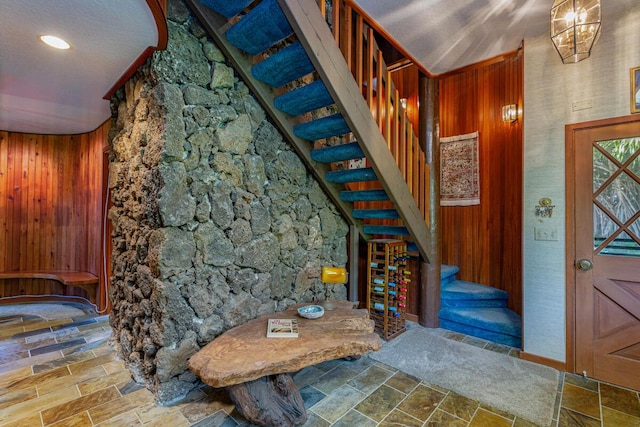 foyer with wooden walls and a textured ceiling