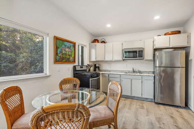 kitchen featuring gray cabinetry, sink, stainless steel appliances, light hardwood / wood-style flooring, and lofted ceiling