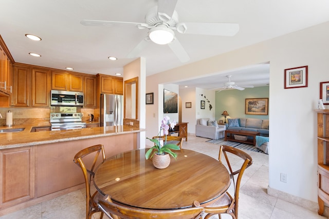 tiled dining area featuring ceiling fan and sink