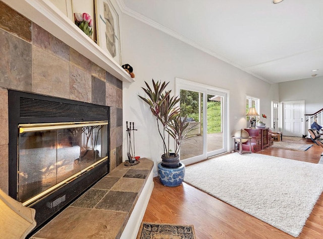 living room with a tile fireplace, wood-type flooring, lofted ceiling, and ornamental molding