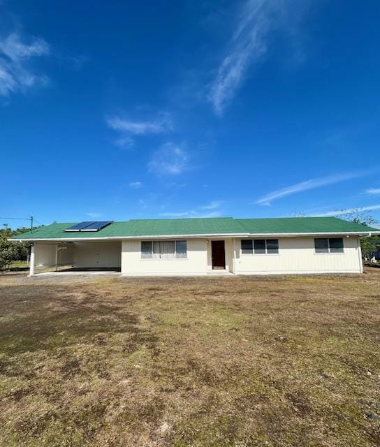 ranch-style home featuring a front lawn and solar panels