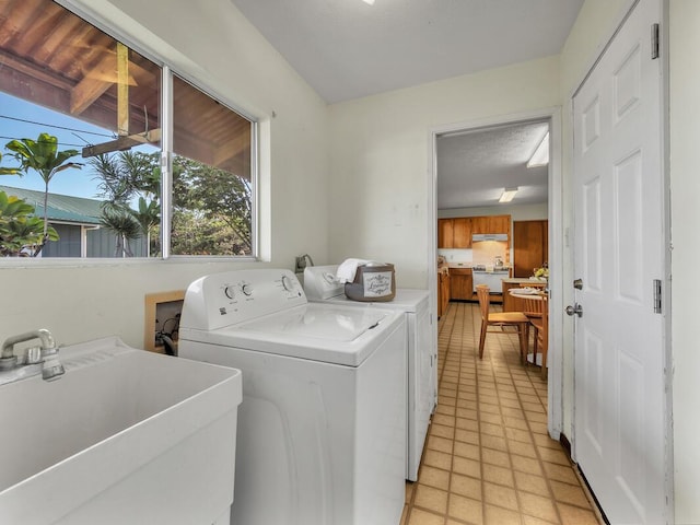 clothes washing area featuring light tile patterned floors, separate washer and dryer, and sink