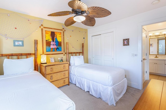 carpeted bedroom with sink, ensuite bathroom, a closet, and ceiling fan