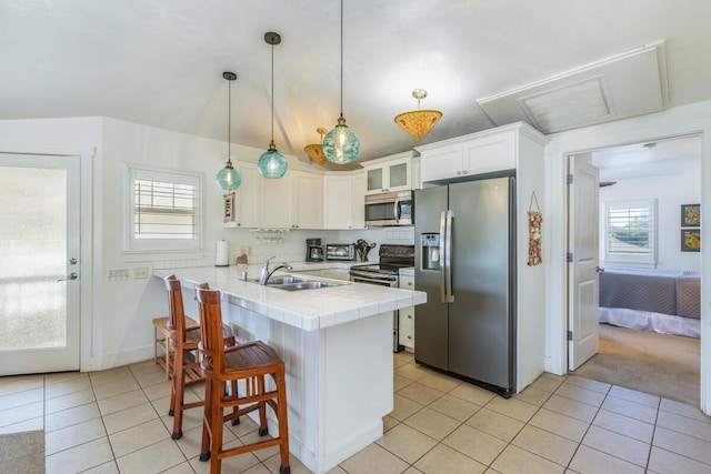 kitchen with white cabinets, sink, appliances with stainless steel finishes, decorative light fixtures, and kitchen peninsula