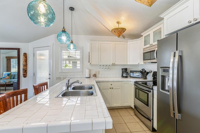 kitchen featuring sink, hanging light fixtures, tile counters, white cabinetry, and stainless steel appliances