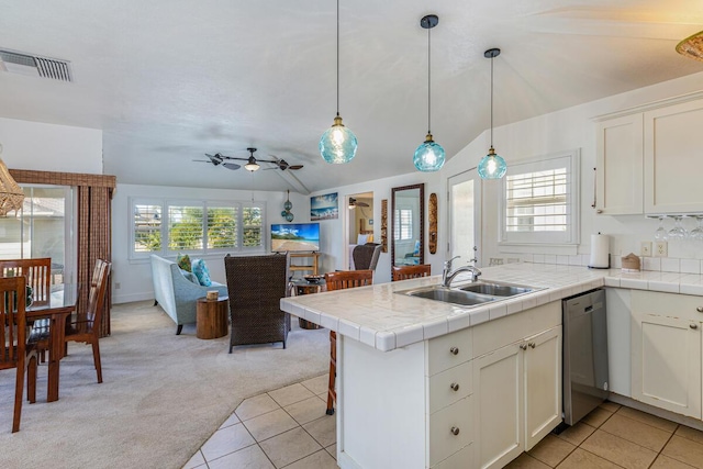 kitchen featuring light carpet, sink, stainless steel dishwasher, decorative light fixtures, and kitchen peninsula