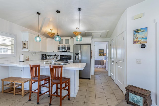 kitchen featuring kitchen peninsula, appliances with stainless steel finishes, a breakfast bar, and white cabinetry