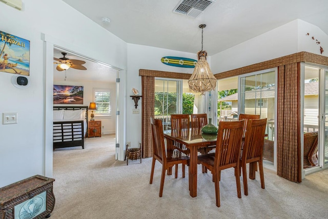 dining space with ceiling fan with notable chandelier and light colored carpet