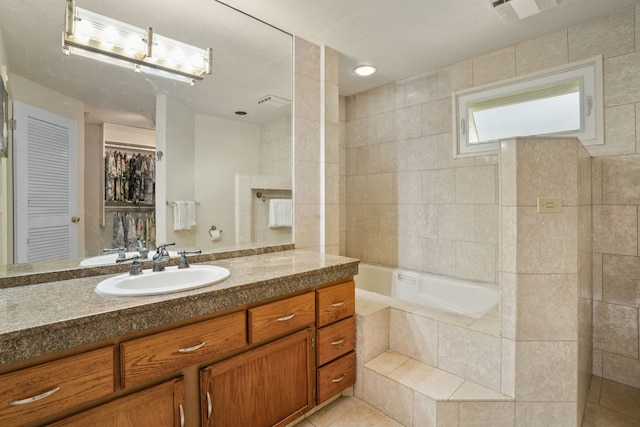 bathroom with tile patterned flooring, vanity, tiled bath, and tile walls