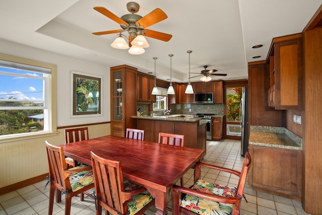 tiled dining space featuring ceiling fan, wood walls, and sink