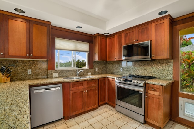 kitchen with sink, light stone countertops, stainless steel appliances, and tasteful backsplash