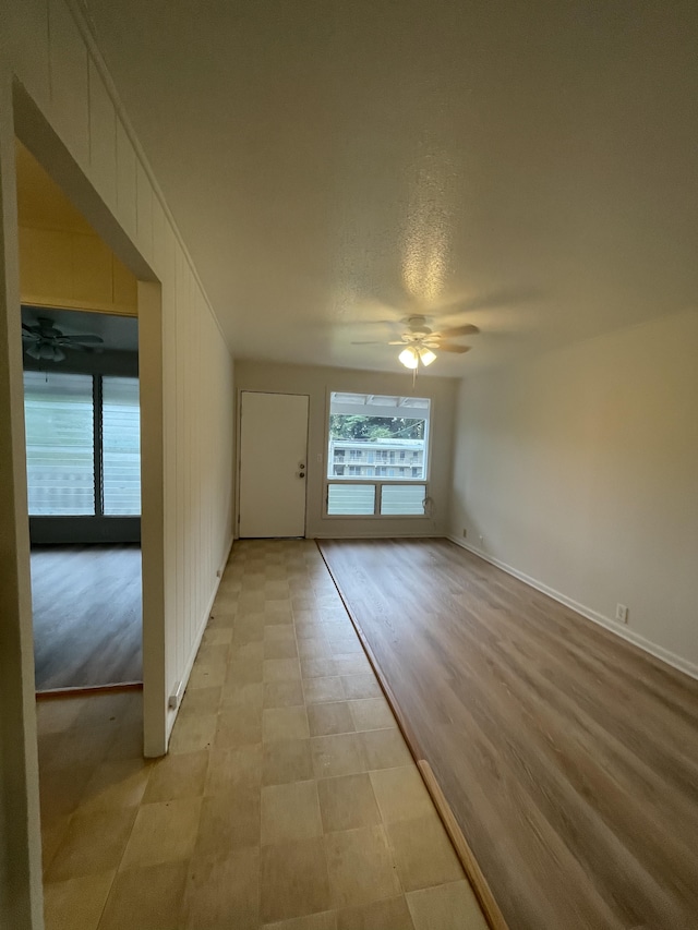 spare room featuring a textured ceiling, light wood-type flooring, and ceiling fan