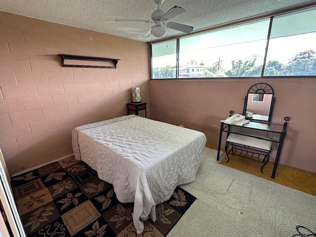 carpeted bedroom with ceiling fan and a textured ceiling