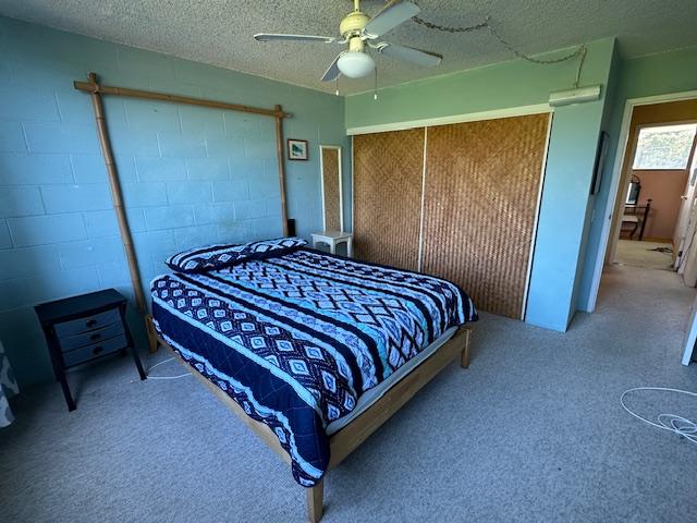 carpeted bedroom featuring ceiling fan and a textured ceiling