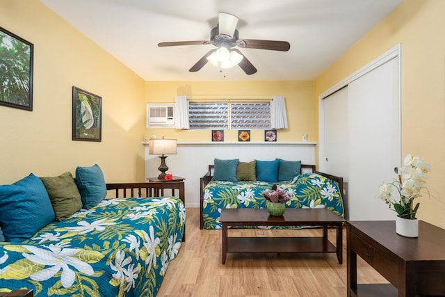 bedroom with a closet, a wall unit AC, ceiling fan, and light hardwood / wood-style floors