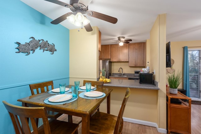 dining room with light hardwood / wood-style flooring, ceiling fan, and sink