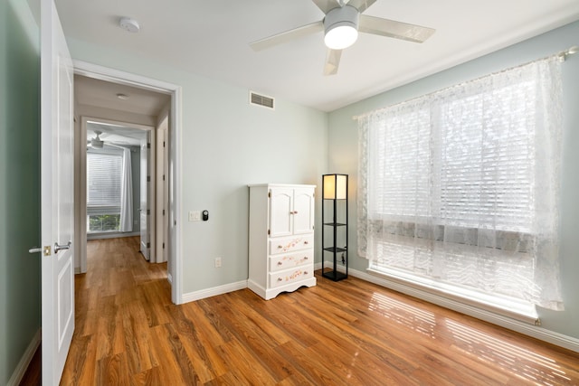 unfurnished bedroom featuring hardwood / wood-style floors, ceiling fan, and multiple windows