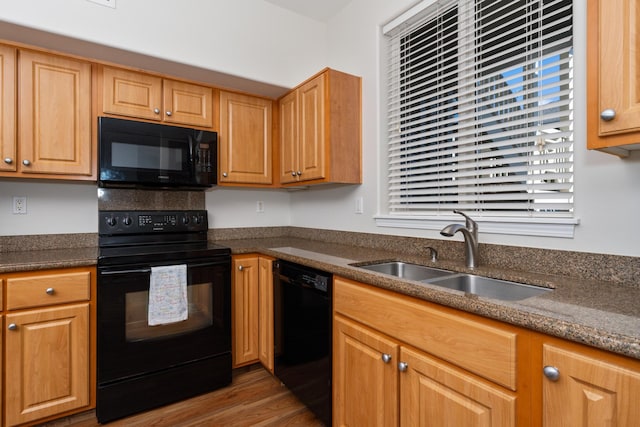 kitchen with dark stone counters, dark hardwood / wood-style flooring, sink, and black appliances