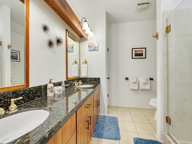 bathroom with a shower with door, vanity, tile patterned floors, and toilet