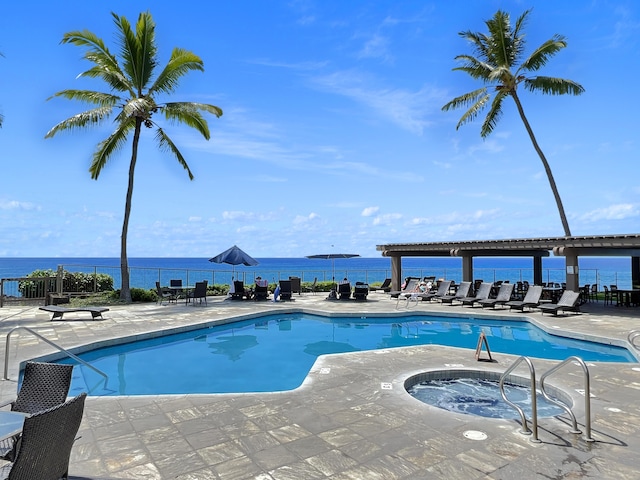 view of pool with a hot tub, a patio, and a water view