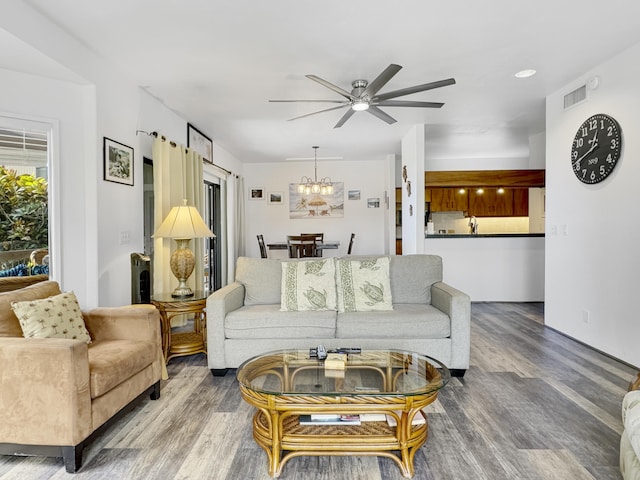 living room with hardwood / wood-style flooring and ceiling fan with notable chandelier