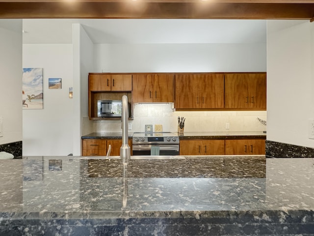 kitchen with dark stone countertops, backsplash, and stainless steel appliances