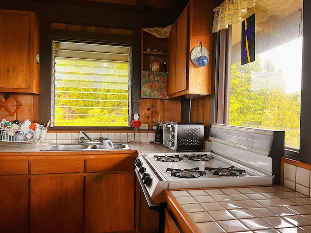 kitchen with range with gas stovetop, tile counters, light tile patterned floors, and sink