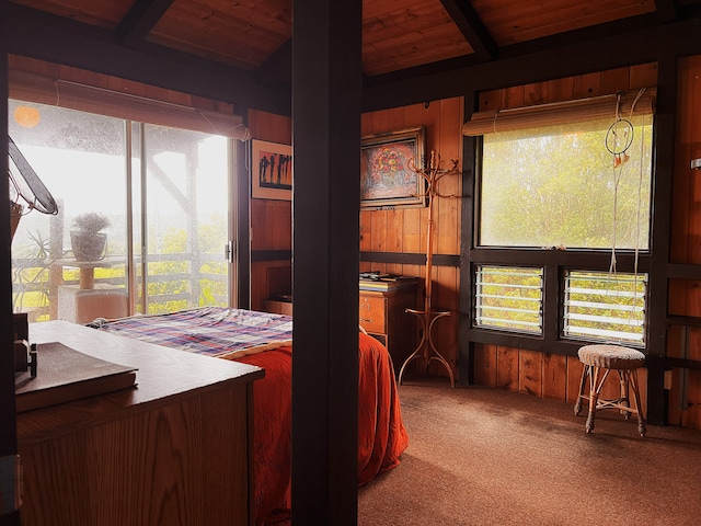 bedroom featuring beam ceiling, wood walls, carpet, and wooden ceiling