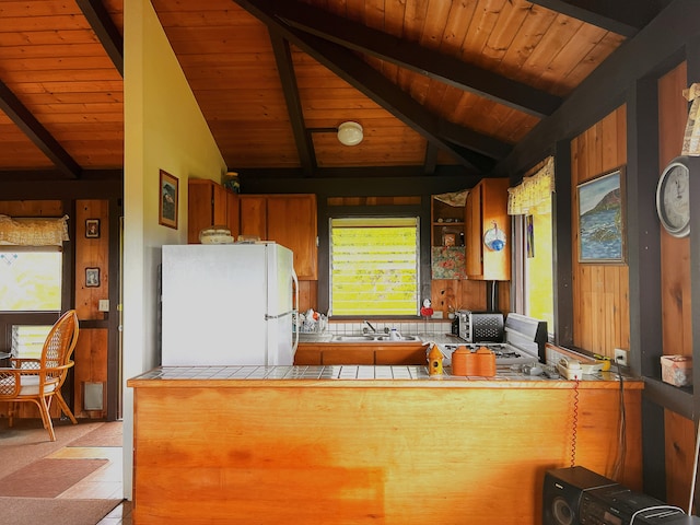 kitchen featuring wooden ceiling, lofted ceiling with beams, kitchen peninsula, tile countertops, and white fridge