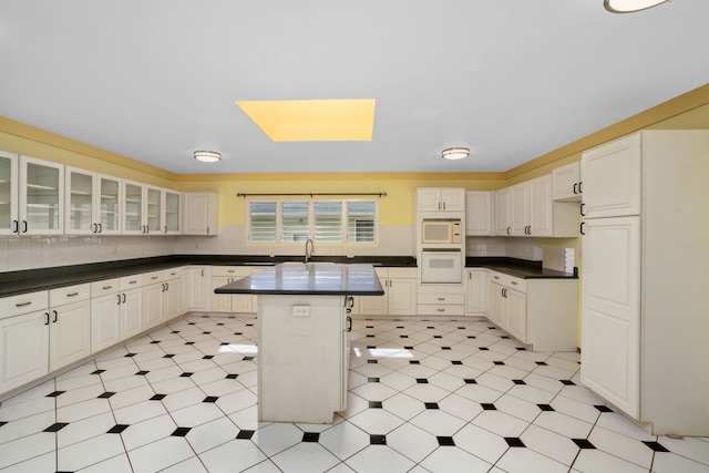 kitchen with white cabinets, a kitchen island, white appliances, and a breakfast bar area