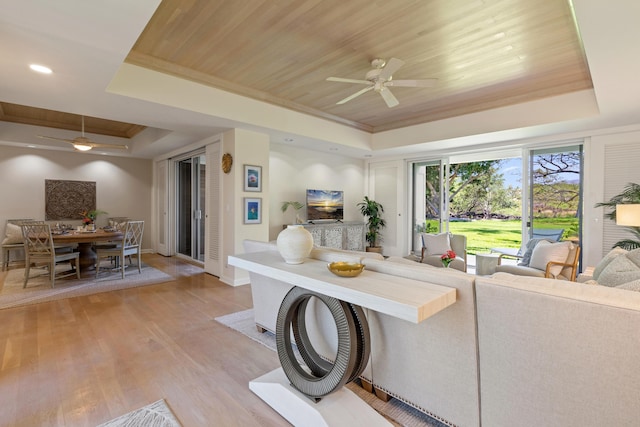 living room featuring light hardwood / wood-style flooring, a raised ceiling, ceiling fan, and wooden ceiling