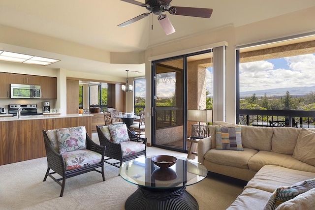 carpeted living room with sink and ceiling fan with notable chandelier