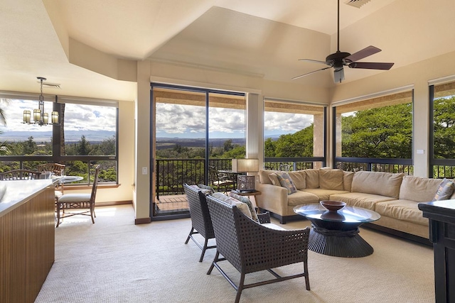 sunroom featuring a tray ceiling and ceiling fan with notable chandelier