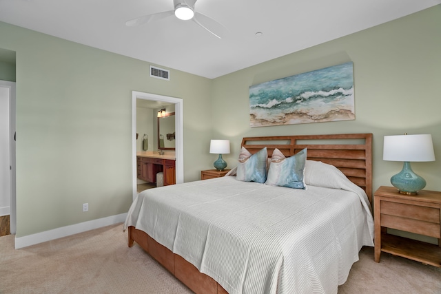 bedroom with ensuite bath, light carpet, and ceiling fan