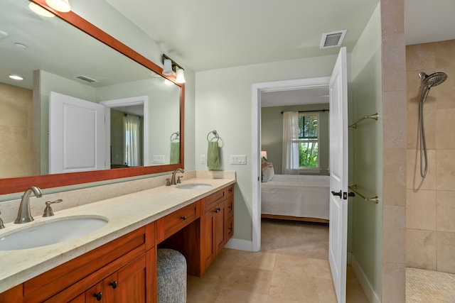 bathroom with tiled shower, vanity, and tile patterned flooring