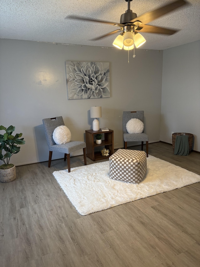 living area with hardwood / wood-style floors, ceiling fan, and a textured ceiling