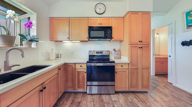 kitchen featuring sink, vaulted ceiling, stainless steel electric stove, decorative backsplash, and light wood-type flooring