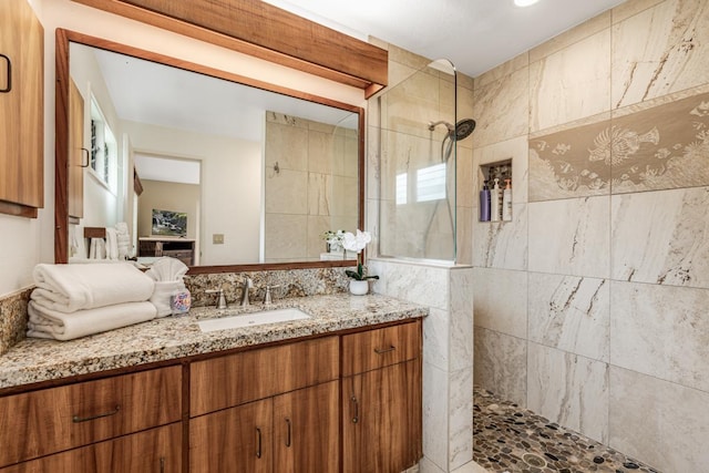 bathroom with vanity, a tile shower, and tile walls