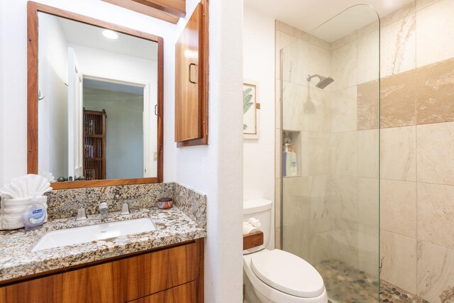 bathroom featuring tiled shower, vanity, and toilet