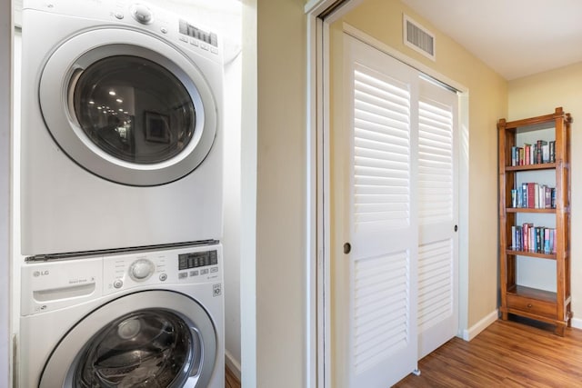 laundry area featuring hardwood / wood-style floors and stacked washer and clothes dryer