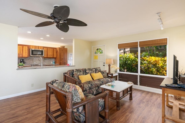 living room with ceiling fan, dark hardwood / wood-style flooring, track lighting, and sink