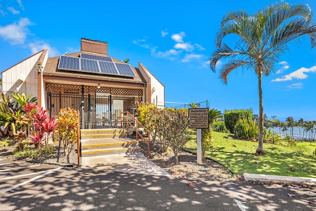 exterior space featuring solar panels, covered porch, and a front lawn