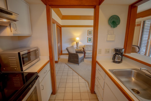 kitchen with stainless steel appliances, exhaust hood, sink, white cabinets, and light tile patterned flooring