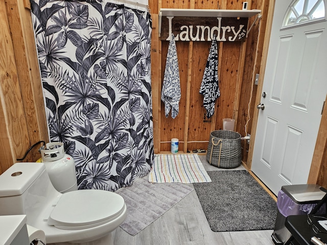 bathroom with wooden walls, toilet, and hardwood / wood-style flooring