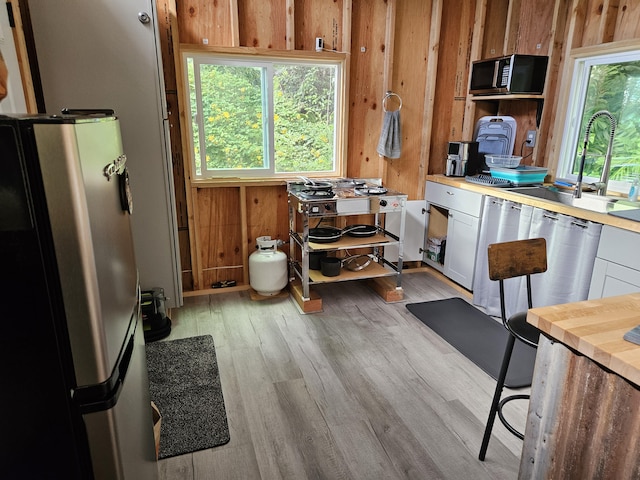 interior space featuring wood walls, sink, and light hardwood / wood-style flooring