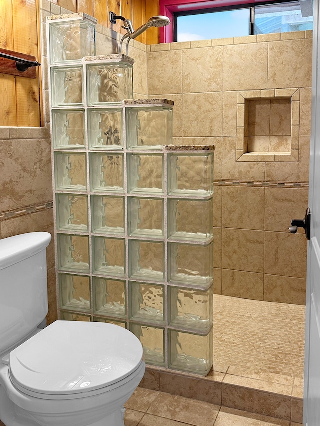 bathroom with toilet, tile patterned flooring, tile walls, and walk in shower