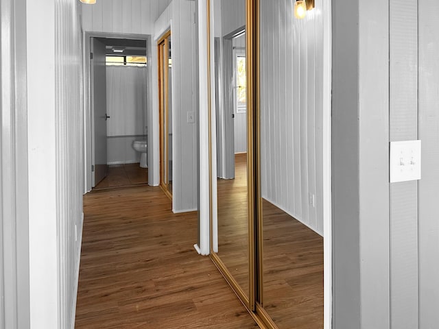 corridor featuring dark hardwood / wood-style floors and wooden walls