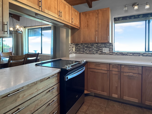 kitchen featuring backsplash, black range with electric stovetop, dark tile patterned floors, and a chandelier