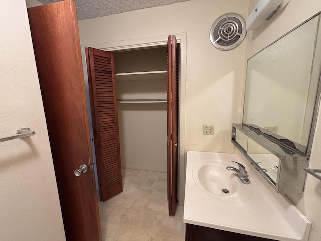 bathroom with a textured ceiling, a closet, and vanity